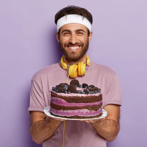 Ein Sportler hält eine Torte in der Hand und lächelt (Bebilderung Doping mit Backpulver)