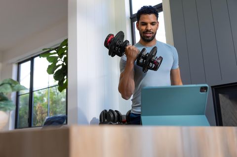 Sportlicher Mann trainiert mit den 552i Dumbbells von BowFlex im Wonzimmer