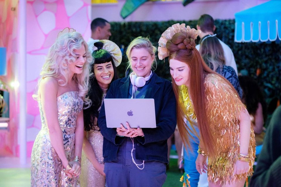 Die 4 Frauen stehen um einen Laptop herum und schauen lächelnd darauf.