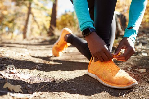 Apple Watch Vergleich: Eine Frau bindet sich ihre Schuhe für ihren Waldlauf