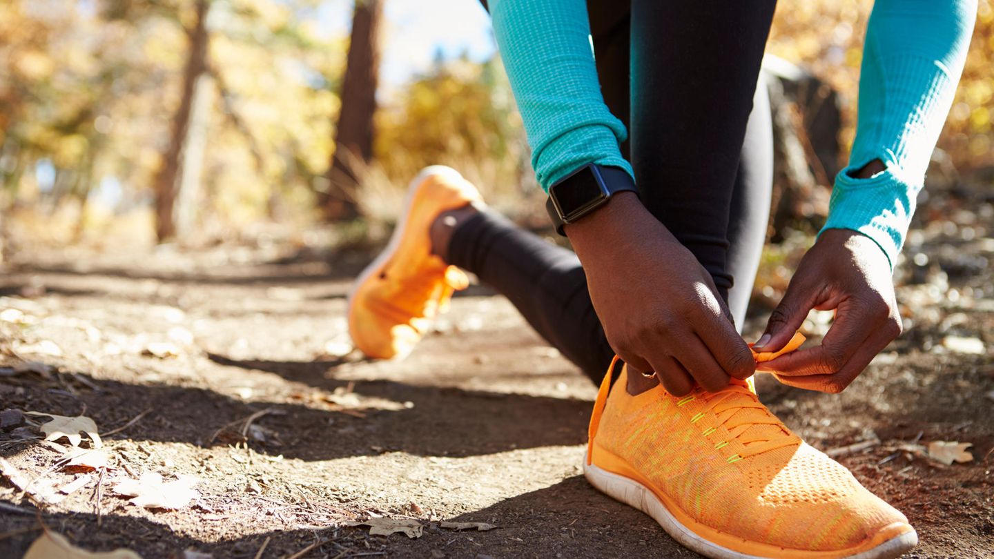 Apple Watch Vergleich: Eine Frau bindet sich ihre Schuhe für ihren Waldlauf