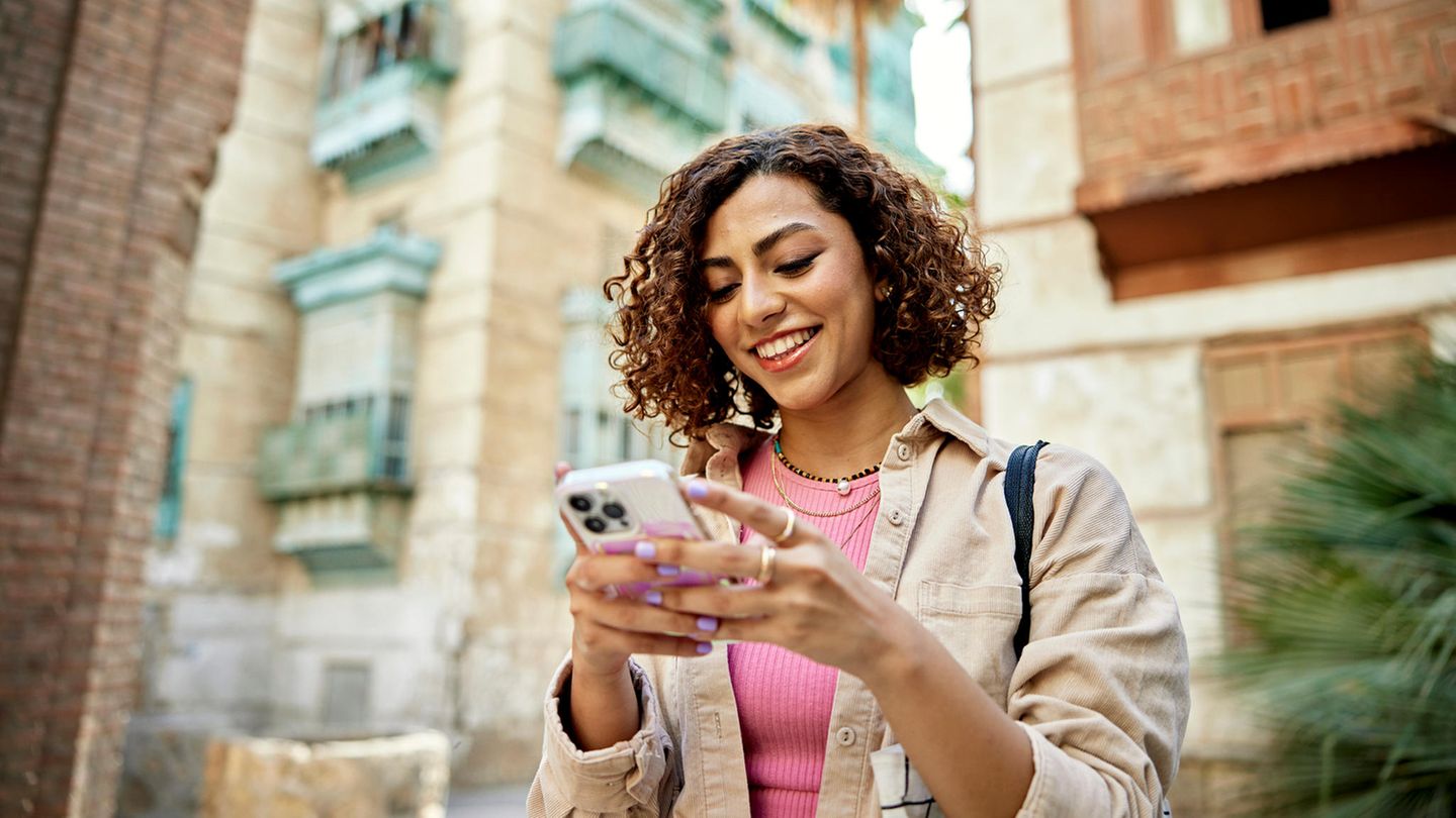 Junge Frau mit Smartphone in einer kleinen Gasse