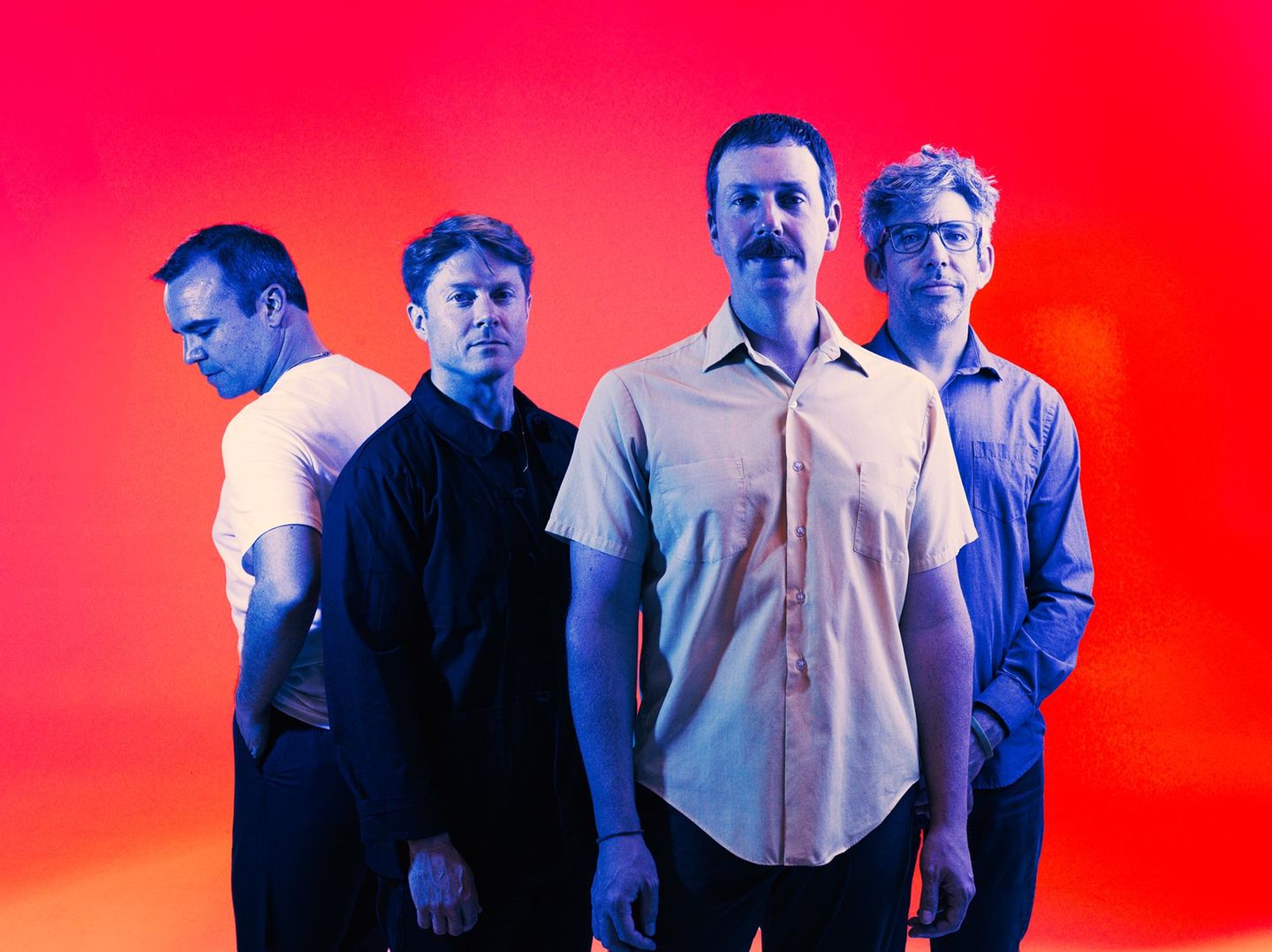 Die Band Future Islands, vier mittelalte Männer vor rotem Hintergrund