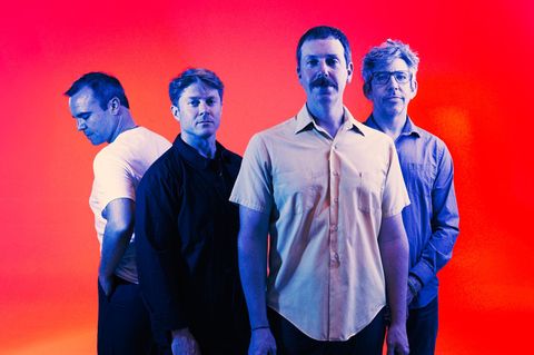Die Band Future Islands, vier mittelalte Männer vor rotem Hintergrund