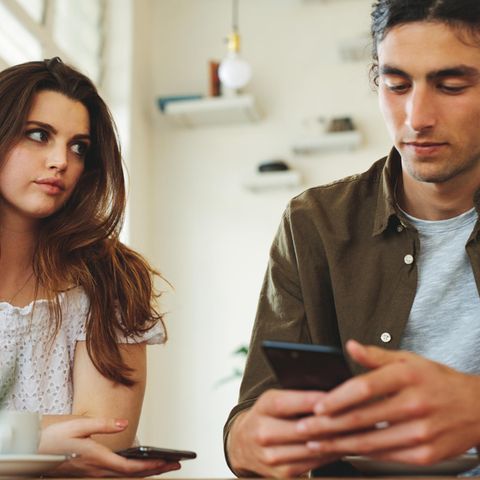 Frau guckt genervt, Mann guckt aufs Handy