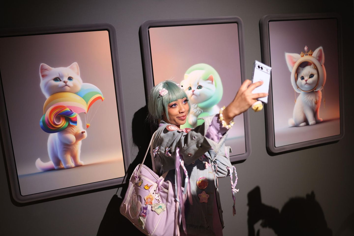 Eine Besucherin fotografiert sich vor KI-generierten Katzenbildern auf der Ausstellung CUTE, die am 25. Januar in der Londoner Galerie Somerset House eröffnete. 
