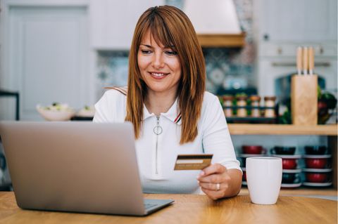 Frau mit goldener Kreditkarte (American Express) am Rechner.