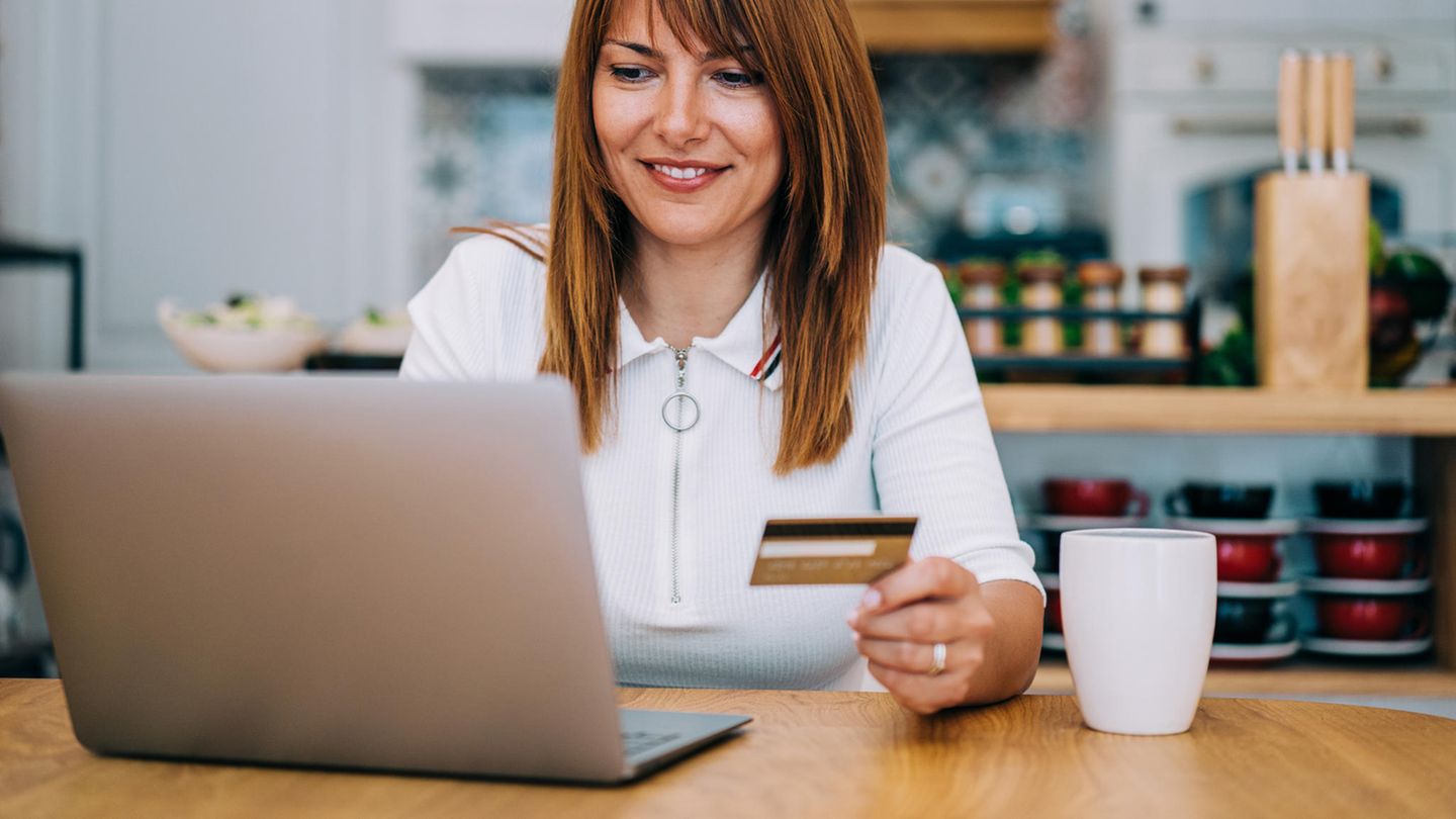 Frau mit goldener Kreditkarte (American Express) am Rechner.