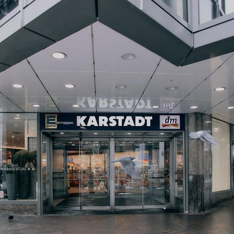 Vor dem Eingang der Karstadt Filliale in Lübeck fliegen zwei Tauben
