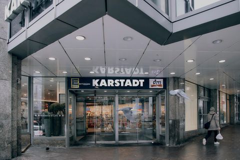 Vor dem Eingang der Karstadt Filliale in Lübeck fliegen zwei Tauben