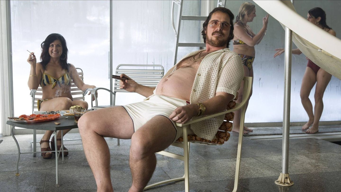 Christian Bale sitzt nur mit Shorts und offenem Hemd bekleidet auf einem Gartenstuhl Christian Bale sitzt nur mit Shorts und offenem Hemd bekleidet auf einem Gartenstuhl