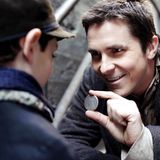 Christian Bale zeigt einem Jungen eine Münze