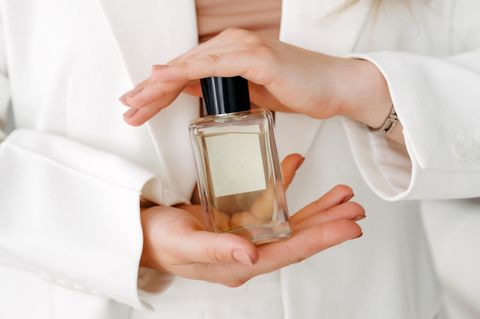 Person hält Parfum mit dem Duft frischer Wäsche in der Hand