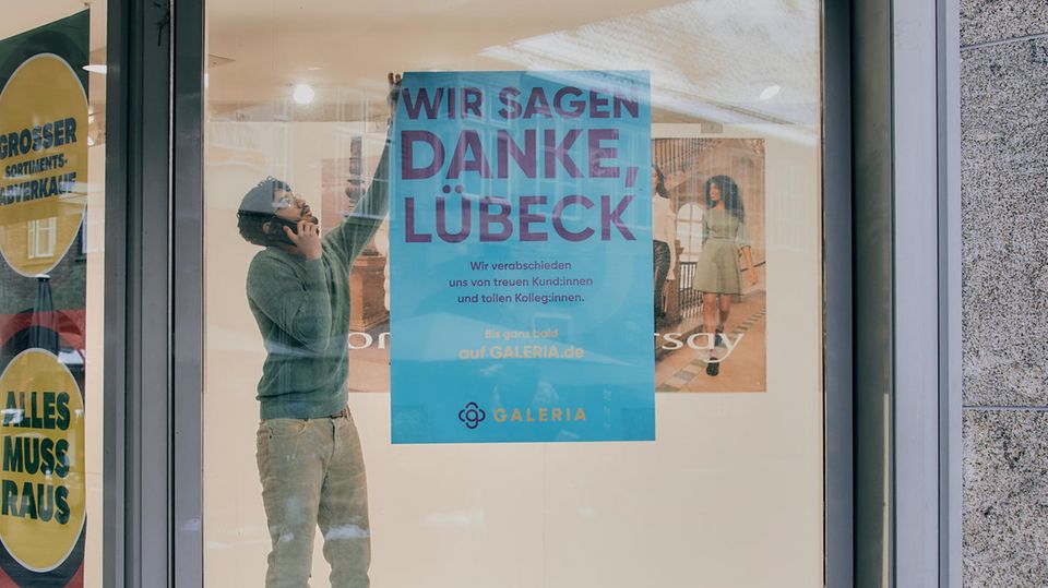 Een medewerker van de Karstadt-Filiale in Lübeck hangt een plaquette aan een vel papier