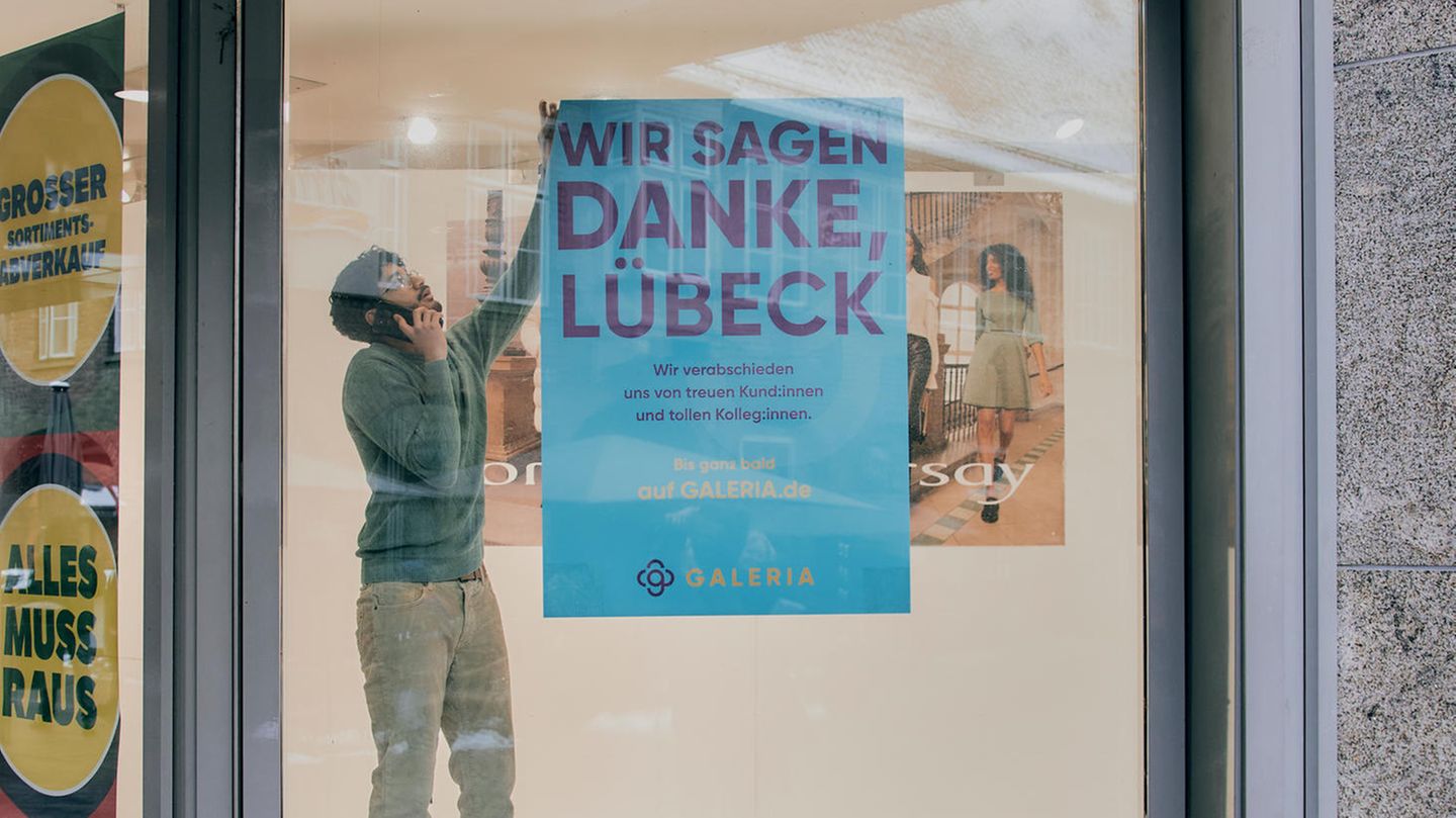 Ein Mitarbeiter der Karstadt-Filiale in Lübeck hängt ein Plakat von einer Scheibe ab