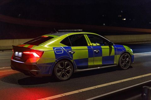 Ein britisches Polizeiauto steht in der Dunkelheit auf einer Straße.