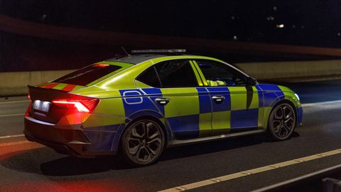 Ein britisches Polizeiauto steht in der Dunkelheit auf einer Straße.