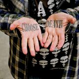Ein Mann zeigt seine Hände, auf deren Innenflächen „Choose Death“ tätowiert ist