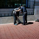 Ein Polizist versucht einem Mann die Fernsteuerung eines ferngelenkten Spielzeugautos zu entreißen