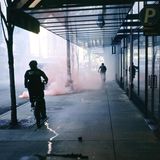 Zwei Polizisten auf Fahrrädern vor dem Rauch einer Rauchbombe