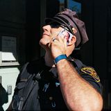 Ein Polizist blickt nach oben, während er mit seinem Smartphone telefoniert