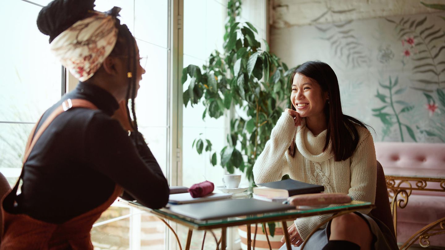 Zwei Frauen unterhalten sich in einem Café und hören einander zu Zwei Frauen unterhalten sich in einem Café und hören einander zu