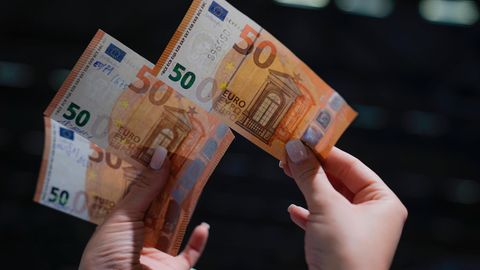 Eine Frau hält in der rechten Hand einen echten 50-Euro-Schein
