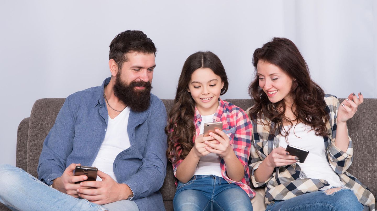 Unbegrenztes Datenvolumen: Familie mit einem Mädchen sitzen auf dem Sofa mit Handys in der Hand.