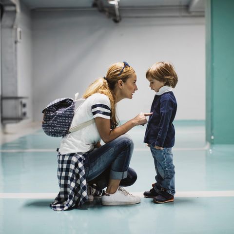 kniende Mutter schimpft, massregelt ihr vorschulkind mit zeigefinger. Sohn schaut traurig mit hängenden schultern.