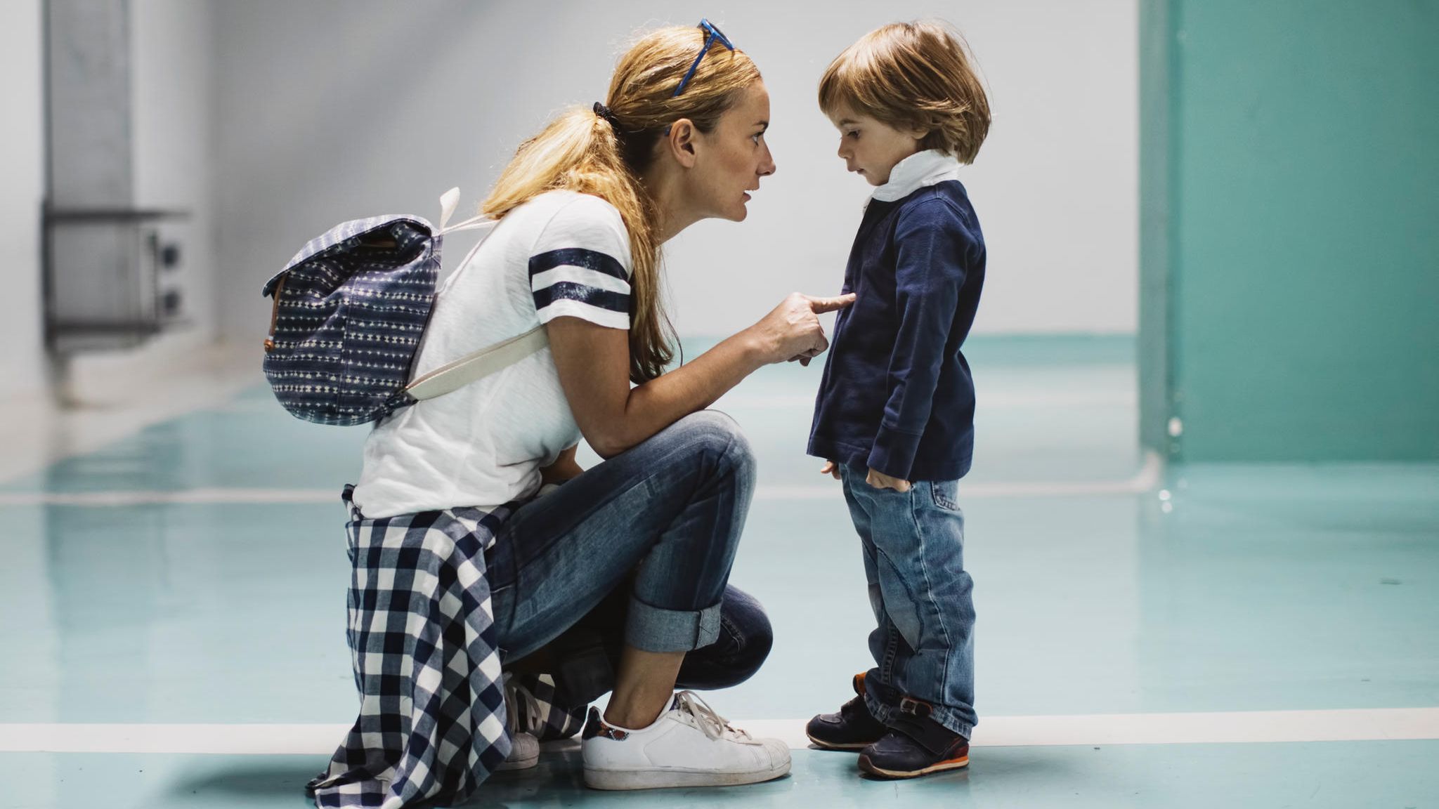 kniende Mutter schimpft, massregelt ihr vorschulkind mit zeigefinger. Sohn schaut traurig mit hängenden schultern.