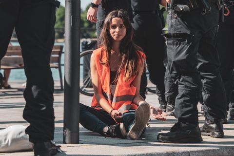 Lea Rhein, Akitivistin der "Letzten Generation", bei einer Blockade, umringt von Polizisten