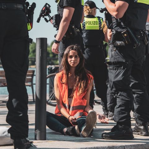 Lea Rhein, Akitivistin der "Letzten Generation", bei einer Blockade, umringt von Polizisten