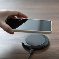 Apple MagSafe: Eine Frau legt ihr iPhone auf ein MacSafe-Ladegerät