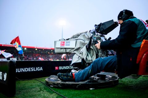 Eine Kamera mit dem Logo der Bundesliga steht am Spielfeldrand eines Fußballstadions
