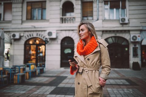 Modische Frau überprüft Apps auf ihrem Smartphone
