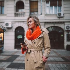 Modische Frau überprüft Apps auf ihrem Smartphone