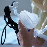 Die linke Hand eines älteren Menschen hält eine Maske zur Beatmung