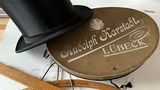 Eine Hutschachtel und ein Zylinder aus der ersten Karstadt-Filiale in Lübeck. Holger Bergt sagt: "Sie stammt aus der Zeit um den Ersten Weltkrieg. Damals war die Firma noch rein im Privateigentum von Rudolph Karstadt und seiner Ehefrau. Erst, als Karstadt 1920 mit Althoff fusionierte, wurde daraus eine AG. Mit der Weltwirtschaftskrise brach alles zusammen wie ein Kartenhaus. Damals hatten Karstadt und Althoff ihre größte Expansionsphase. Aber während der Krise ging das Unternehmen bankrott, weil sie für die Neubauten so viele Kredite aufgenommen hatten. Frau Karstadt sollte ihre Juwelen verkaufen. Nach dem Krieg musste man von ganz vorn anfangen."   