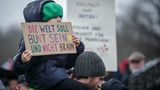 Ein kleines Mädchen hält ein Papp-Plakat in den Händen. Darauf heißt es: "Die Welt soll bunt sein und nicht braun."