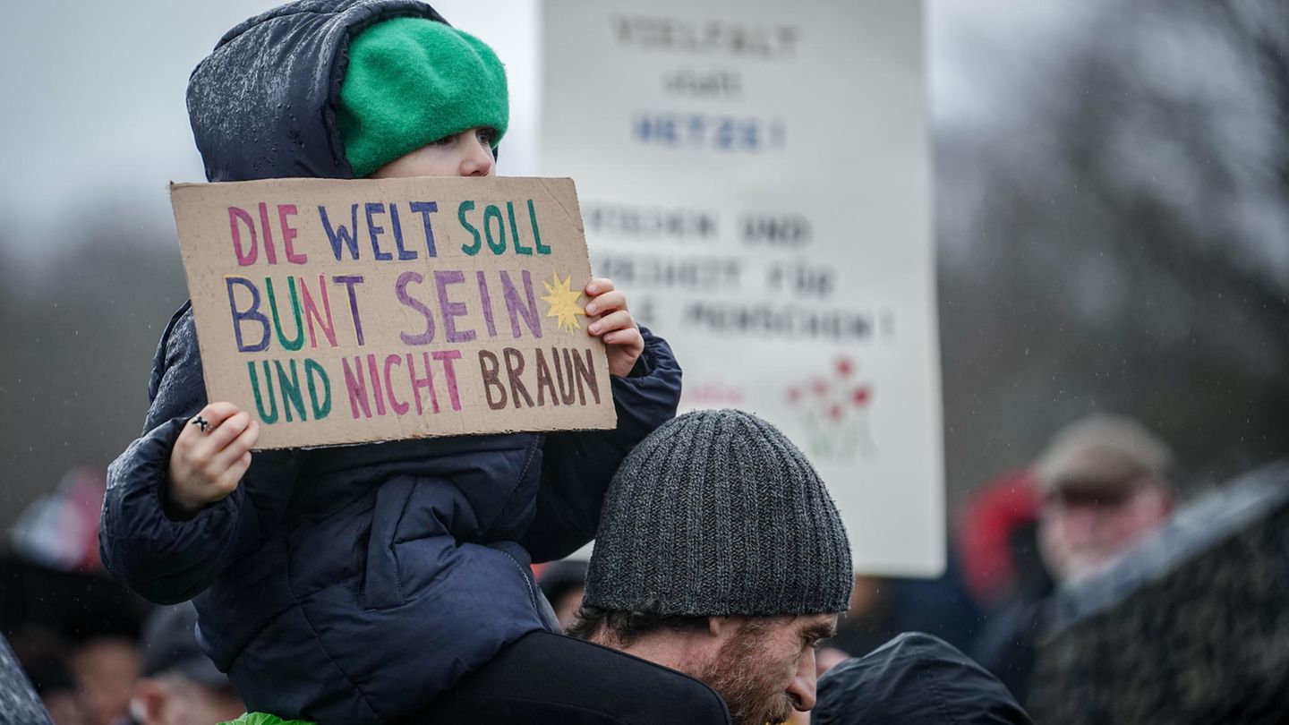 Ein kleines Mädchen hält ein Papp-Plakat in den Händen. Darauf heißt es: "Die Welt soll bunt sein und nicht braun."