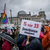 "Faschisten stoppen" steht auf einem Plakat, das ein Demonstrant in die Höhe hält.