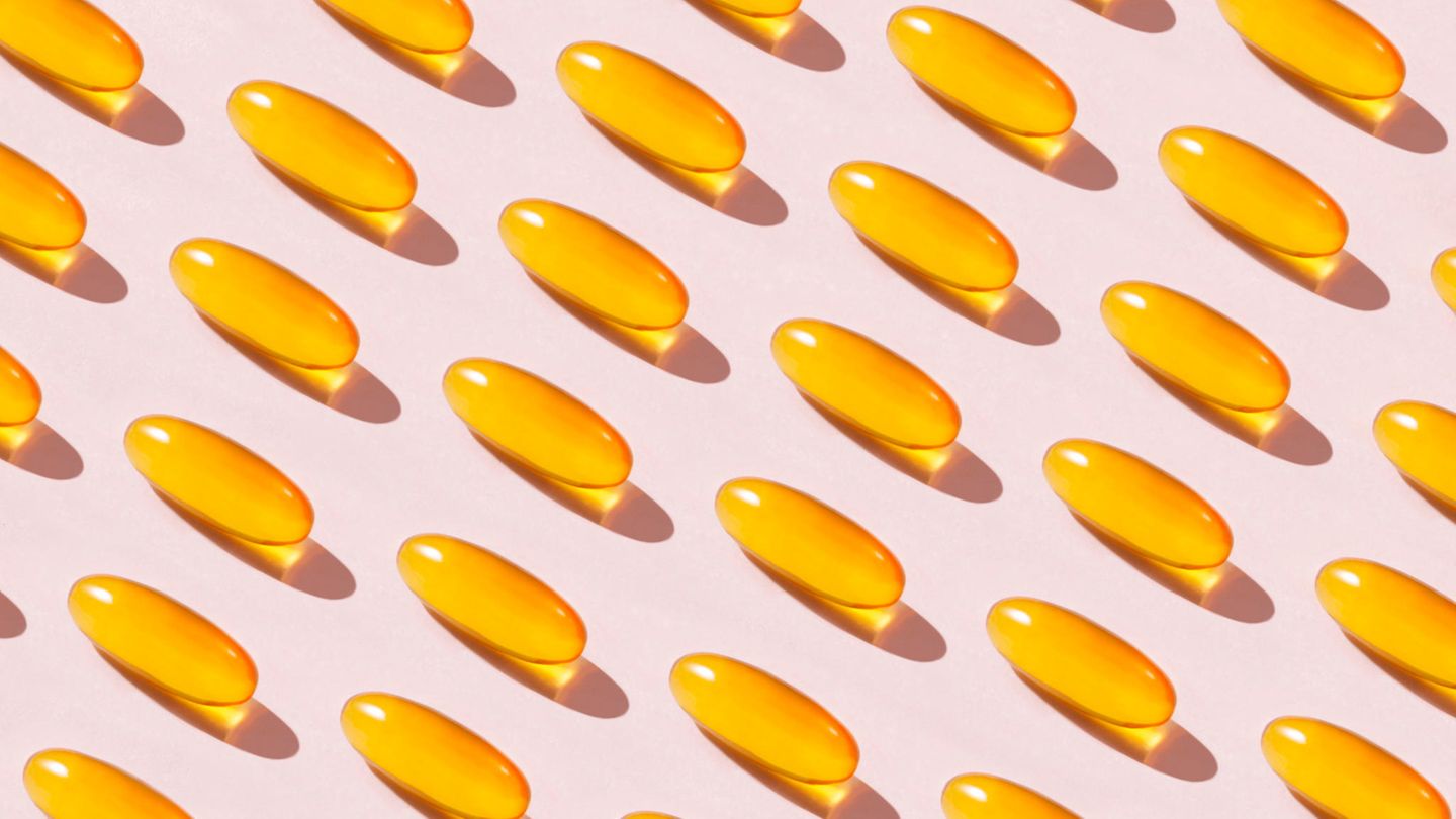 Gelbe Vitamin-D-Dragees auf rosa Hintergrund