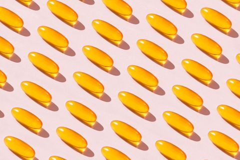 Gelbe Vitamin-D-Dragees auf rosa Hintergrund