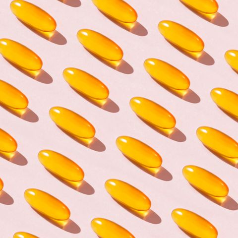 Gelbe Vitamin-D-Dragees auf rosa Hintergrund