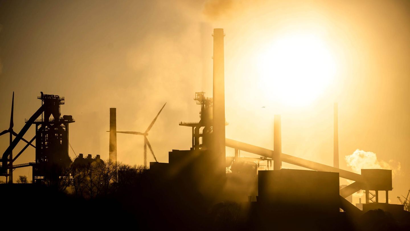 Das Stahlwerk Bremen ragt dunkel vor dem sonnengelben Himmel in die Höhe