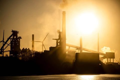 Das Stahlwerk Bremen ragt dunkel vor dem sonnengelben Himmel in die Höhe
