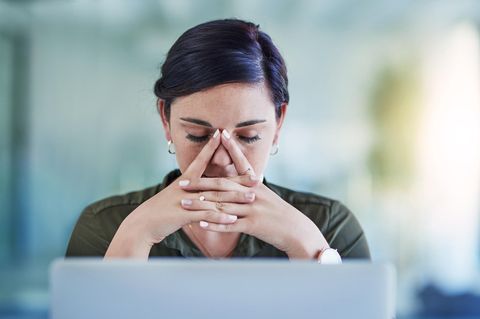 Eine junge Frau sitzt erschöpft am Computer