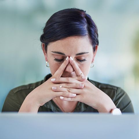 Eine junge Frau sitzt erschöpft am Computer