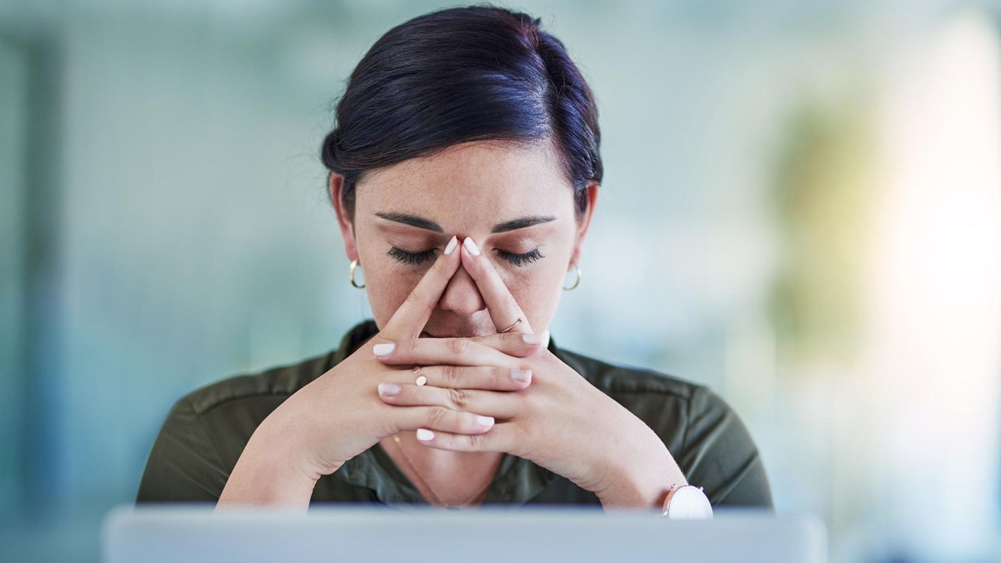Eine junge Frau sitzt erschöpft am Computer