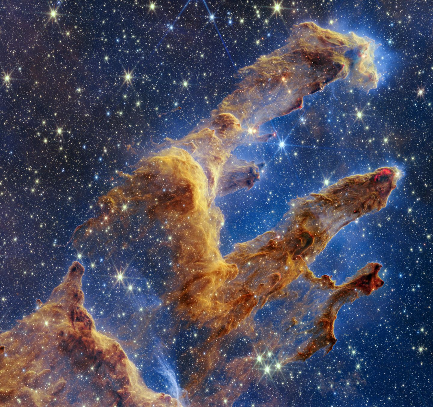 Blick durch den Nebel Schon Hubble lieferte ikonische Bilder der "Säulen der Schöpfung" im 6500 Lichtjahre entfernten Adlernebel. Der Infrarotdetektor des James-Webb-Teleskops zeigt die Sternenfabrik weitaus detaillierter als die Aufnahmen im sichtbaren Licht. Gut zu erkennen sind die hellrot leuchtenden neugeborenen Sterne an den Spitzen der Säulen. Dort ist der Staub am dichtesten, sodass er unter seiner eigenen Gravitation zusammenfällt, sich aufheizt und schließlich neue Sterne entstehen. Hinter den Säulen erscheinen unzählige weitere Sterne und Galaxien